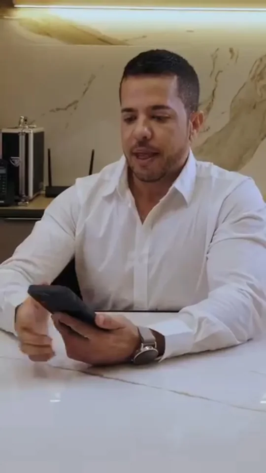 Alexandre Chaves à mesa de mármore do consultório, com o celular na mão